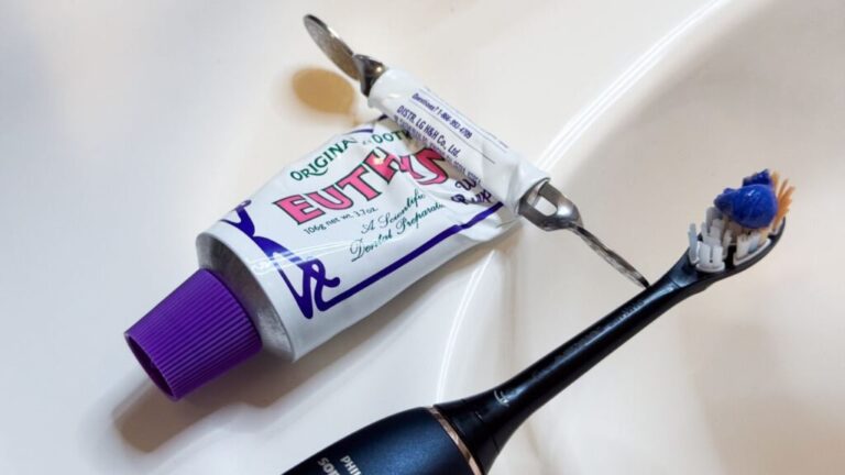 Euthymol Purple Whitening Toothpaste next to toothbrush.