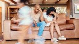 Kids running, stress and parents on sofa tired and chaos in living room with frustrated mom and dad with parenting burnout. Excited children, energy and playing in home with woman and man in crisis.
