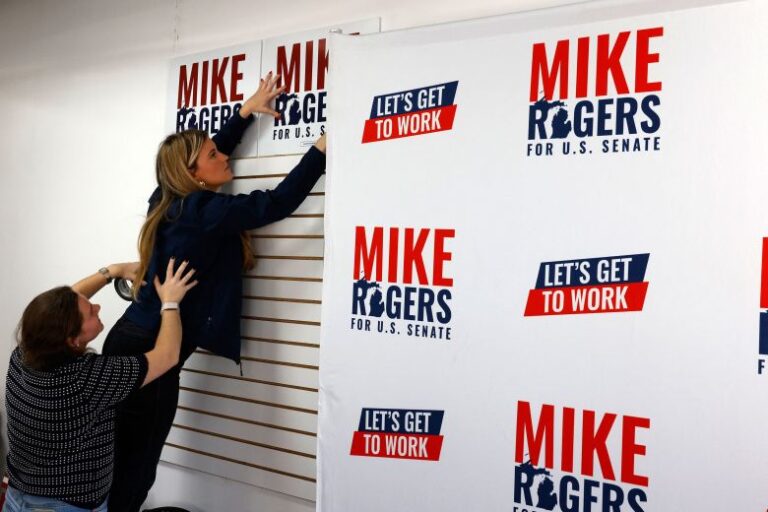 Campaign workers hang signs at the new Rogers campaign office in Detroit on Saturday.