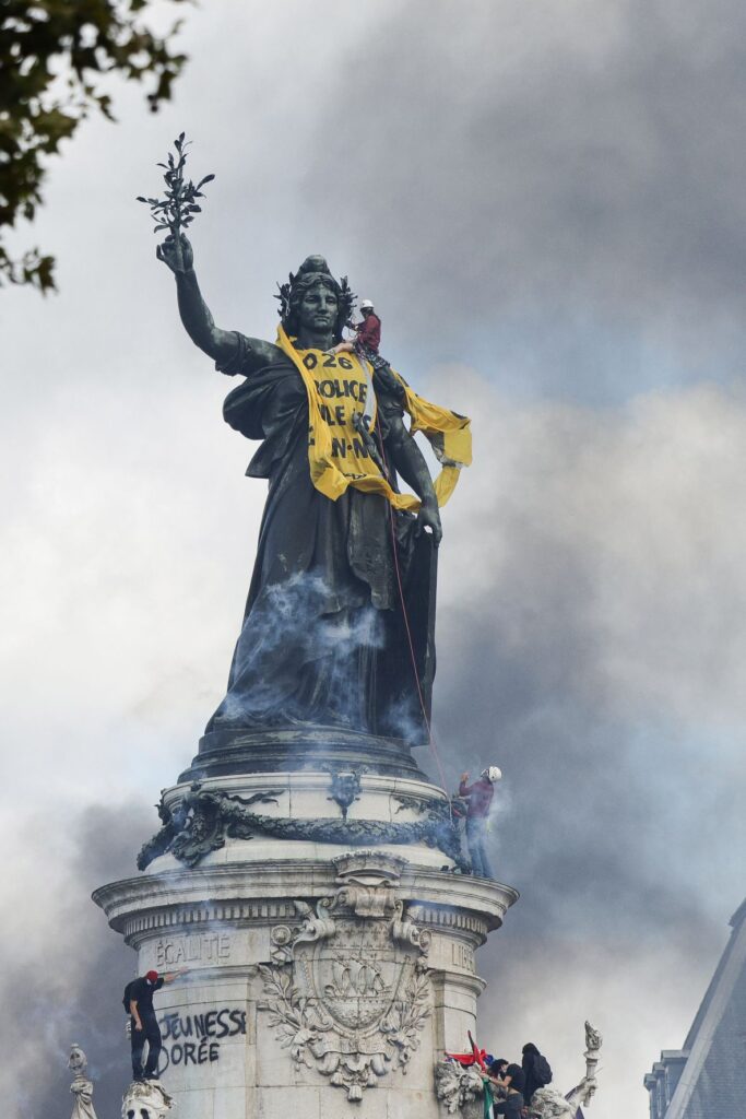 Smoke rises as the 'Statue de la Republique' is covered with a bannner reading