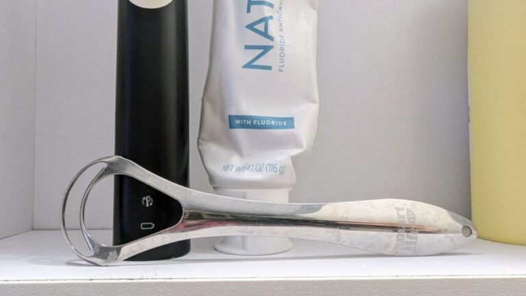 Smart Life Dual Tongue Scrape in front of toothpaste and toothbrush.