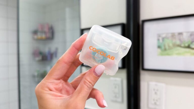Hand holding Cocofloss Woven Dental Floss.